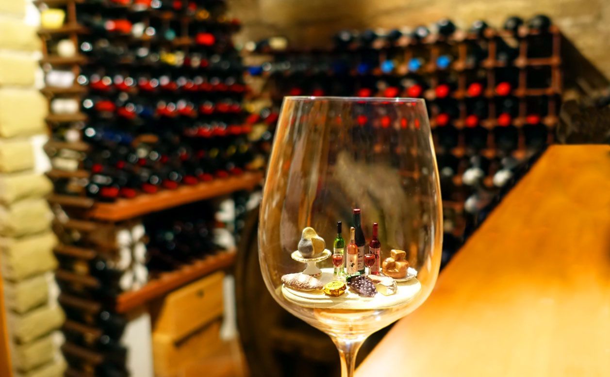 Miniature wine bottles, cheeses and bread in a regular wine glass